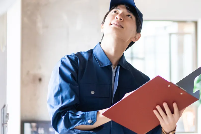 Technician with a clipboard looking up at a ceiling during a home visit